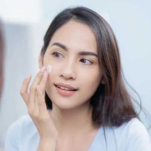 A woman applying retinol moisturiser on her face.